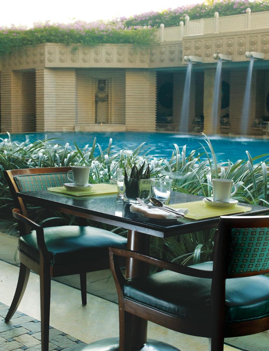 a table and chairs with a pool in the background at Hyderabad Marriott Hotel & Convention Centre in Hyderabad