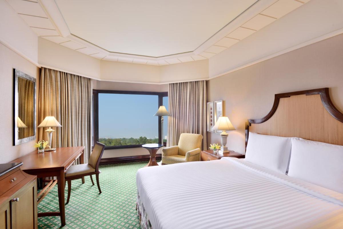 a hotel room with a bed and a desk and a window at Hyderabad Marriott Hotel & Convention Centre in Hyderabad