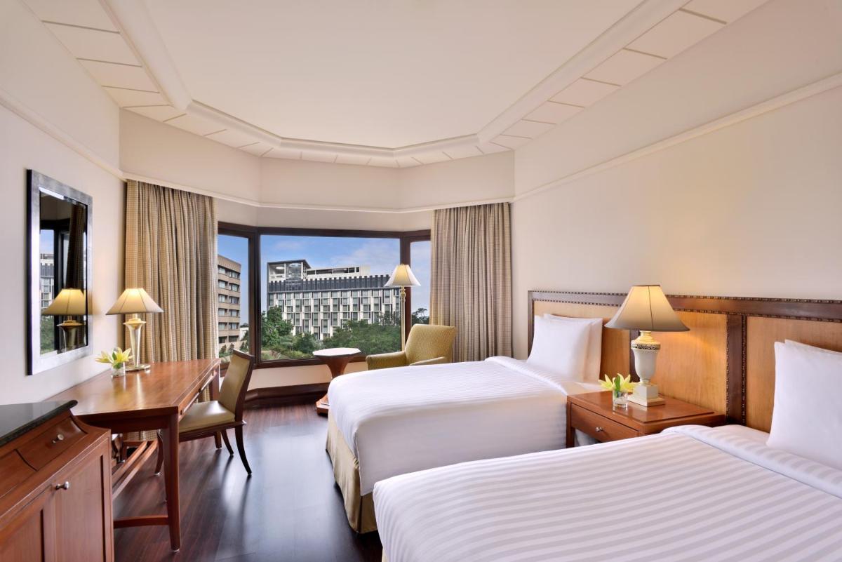 a hotel room with two beds and a desk at Hyderabad Marriott Hotel & Convention Centre in Hyderabad