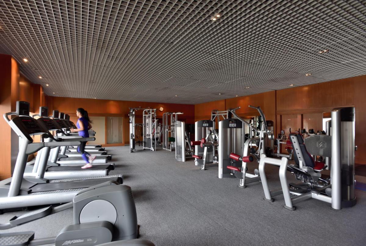 a woman walking through a gym with tread machines at Hyderabad Marriott Hotel & Convention Centre in Hyderabad