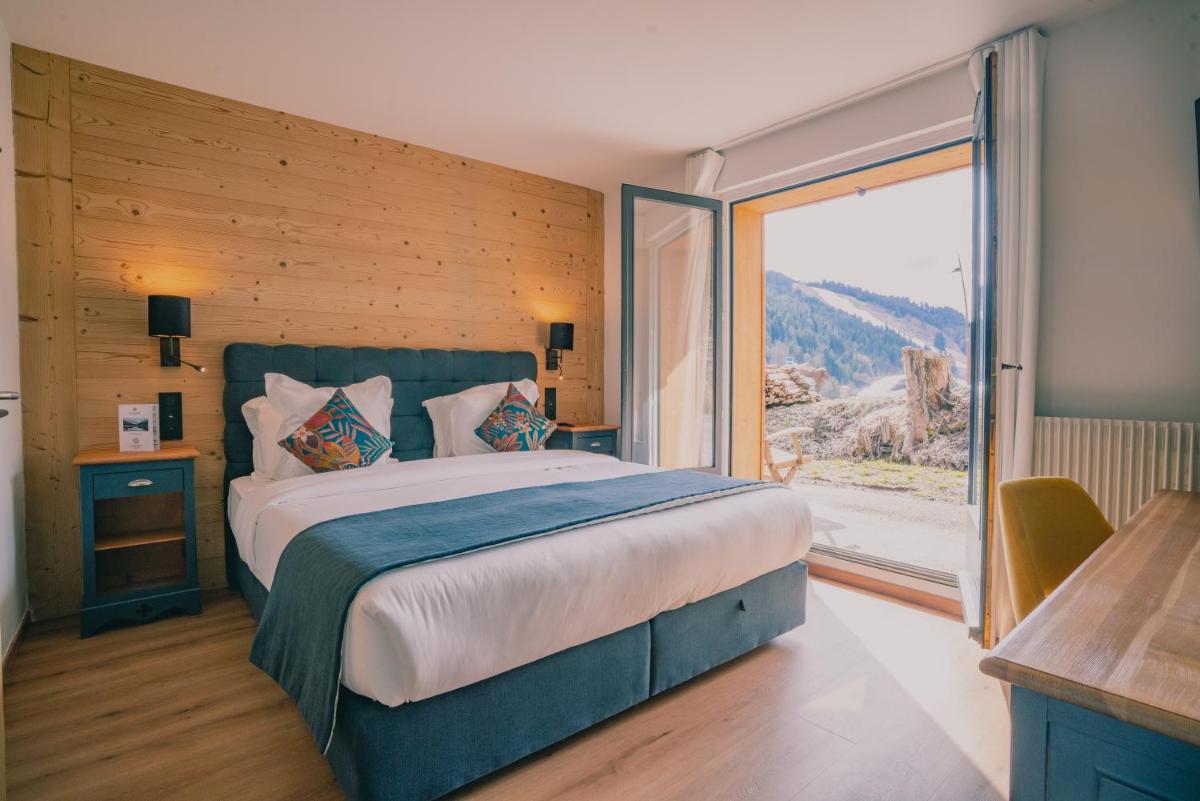 une chambre avec un grand lit et une grande fenêtre dans l'établissement Terra-Beka Lodge, à La Chapelle-dʼAbondance