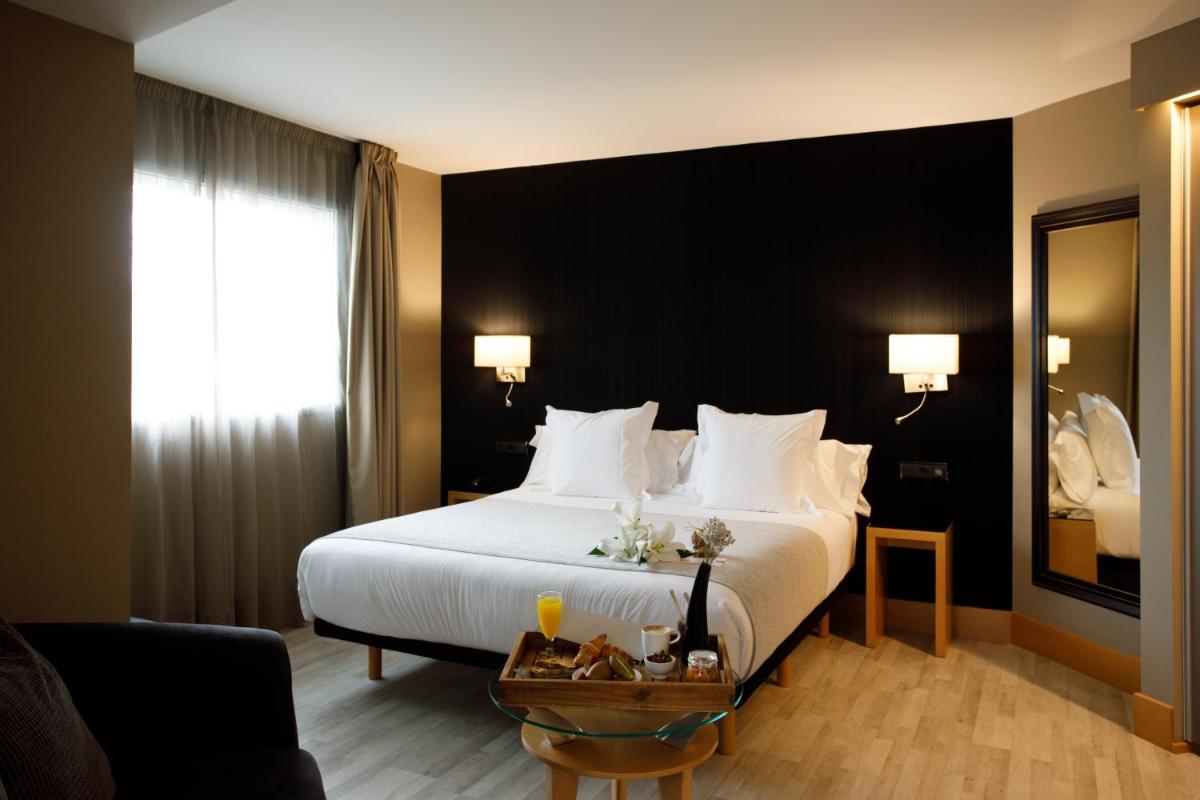 Una habitación de hotel con una cama grande con almohadas blancas. en Hotel Plaza, en A Coruña