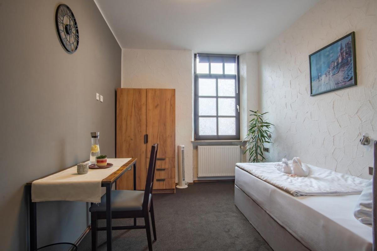 ein kleines Zimmer mit einem Bett, einem Tisch und einem Schreibtisch in der Unterkunft Family and Friends Hassloch in Haßloch