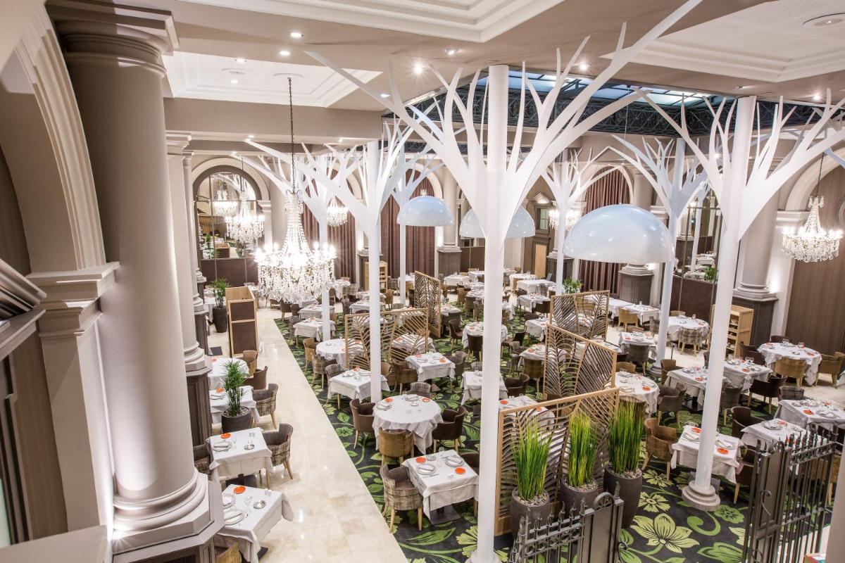 une salle à manger avec des tables blanches et des lustres dans l'établissement Grand Hôtel Des Thermes, à Saint-Malo une salle à manger avec des tables blanches et des lustres dans l'établissement Grand Hôtel Des Thermes, à Saint-Malo