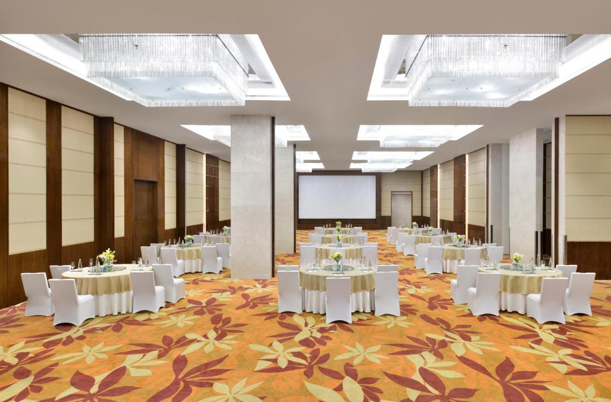 a banquet hall with white tables and a projection screen at Kochi Marriott Hotel in Cochin