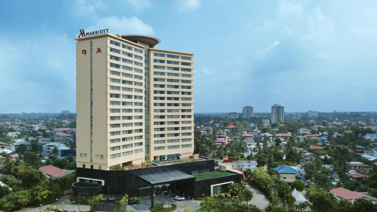 a tall white building with a clock tower in a city at Kochi Marriott Hotel in Cochin
