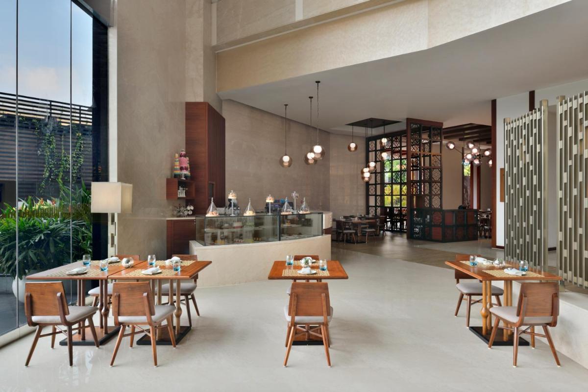 a dining room with wooden tables and chairs at Kochi Marriott Hotel in Cochin