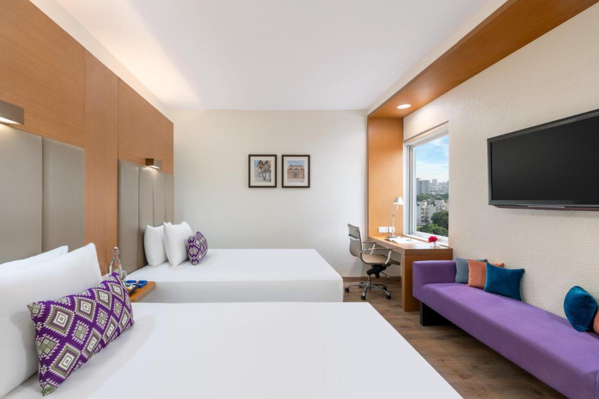 a hotel room with two beds and a flat screen tv at Vivanta Ahmedabad SG Highway in Ahmedabad