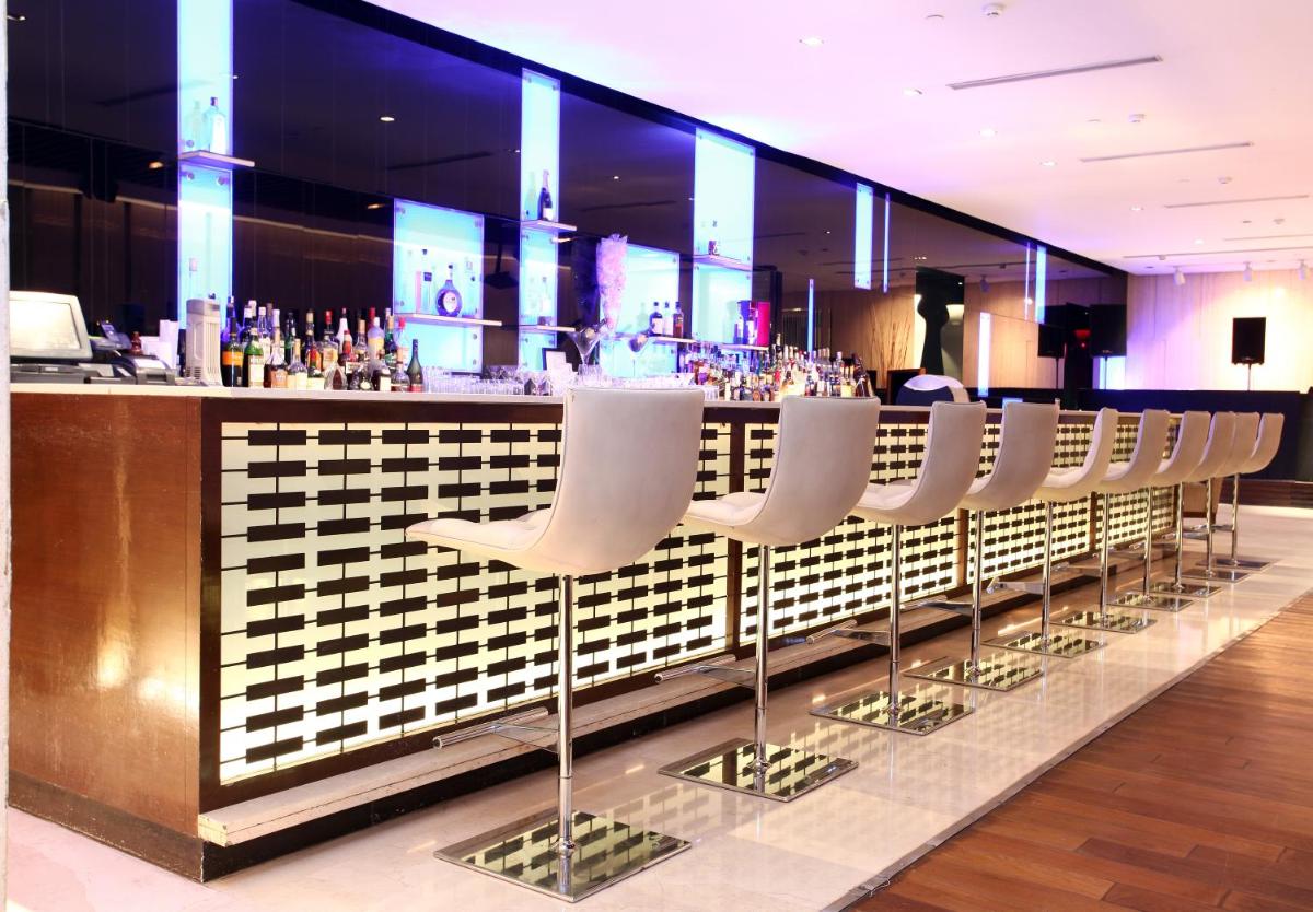 a bar with a row of white chairs at The LaLiT New Delhi in New Delhi