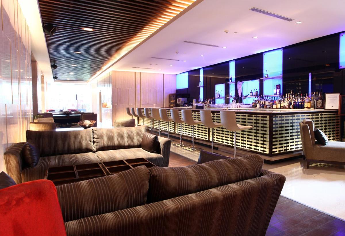 a lobby with couches and a bar in the background at The LaLiT New Delhi in New Delhi