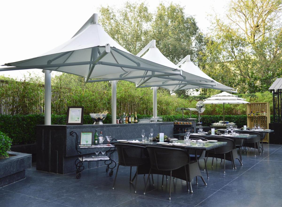 a patio with tables and white umbrellas at The LaLiT New Delhi in New Delhi