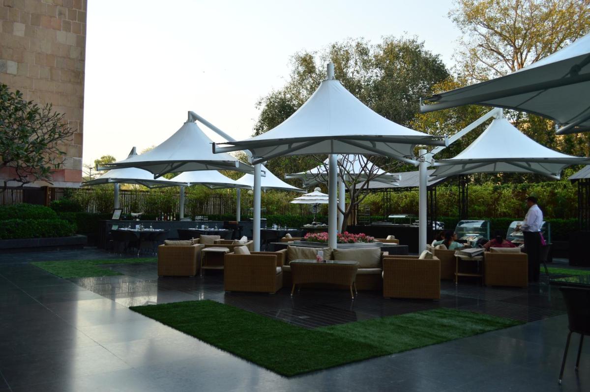 a patio with tables and chairs under umbrellas at The LaLiT New Delhi in New Delhi