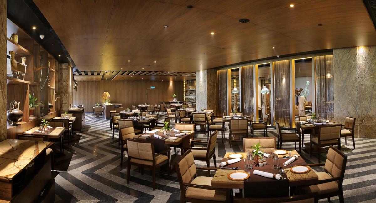 a restaurant with tables and chairs in a room at The LaLiT New Delhi in New Delhi a restaurant with tables and chairs in a room at The LaLiT New Delhi in New Delhi