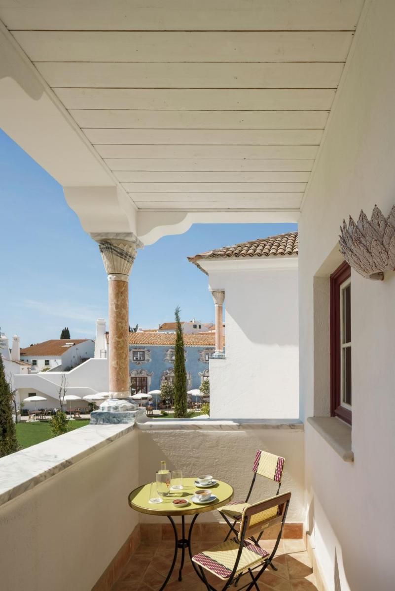 um pátio com uma mesa e cadeiras em uma varanda em Vermelho Melides - Relais & Châteaux em Melides mais 69 fotografias