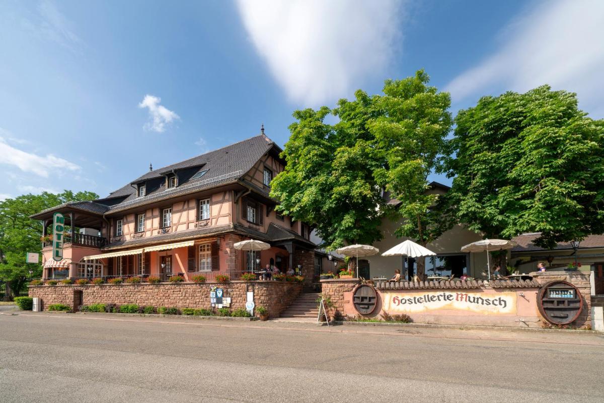 un grand bâtiment en briques avec un restaurant devant dans l'établissement Hotel Munsch Restaurant & Wellness, Colmar Nord - Haut-Koenigsbourg, à Saint-Hippolyte
