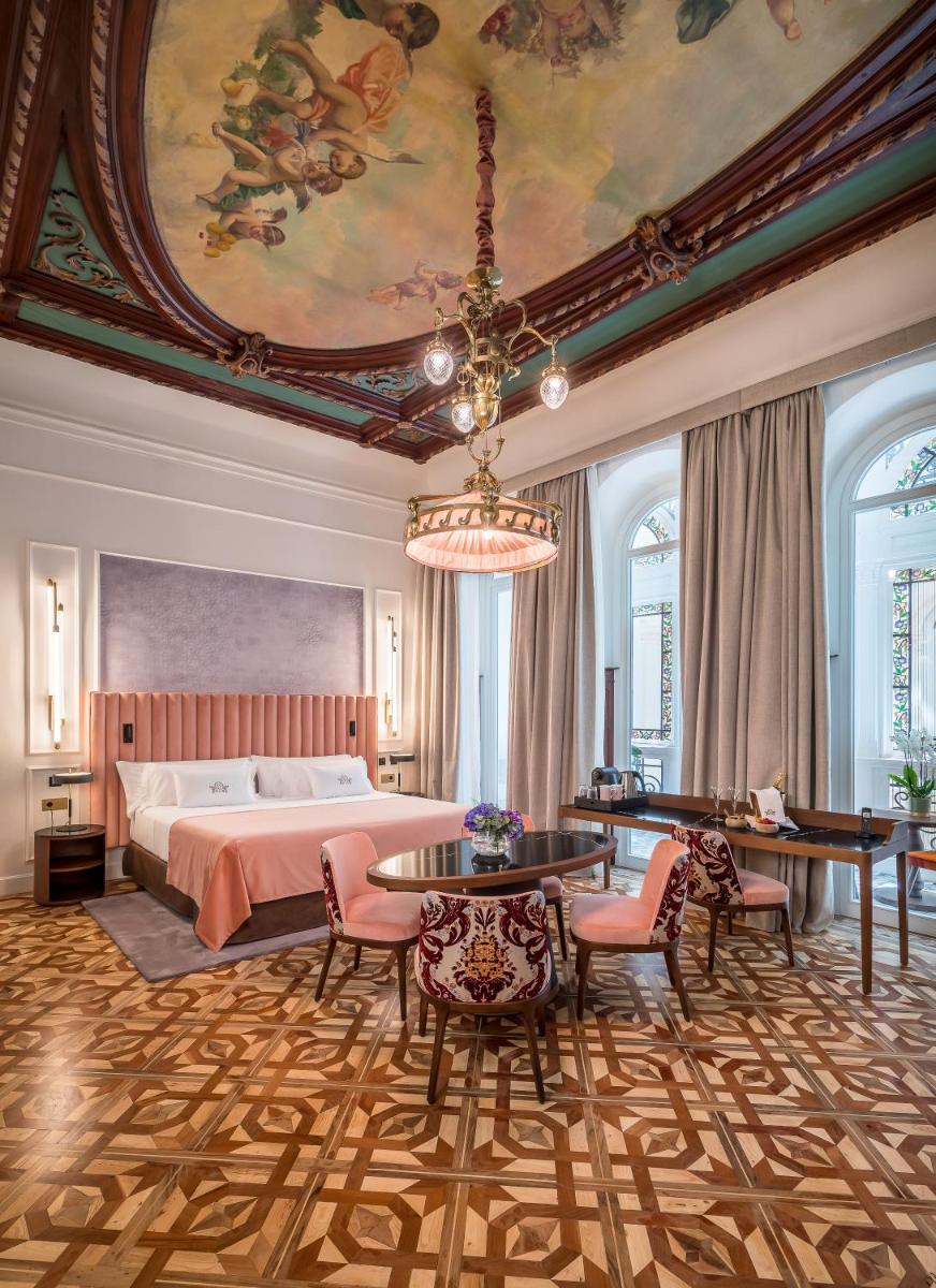Un dormitorio grande con una cama y una lámpara de araña. en Palacio Gran Vía, a Royal Hideaway Hotel, en Granada