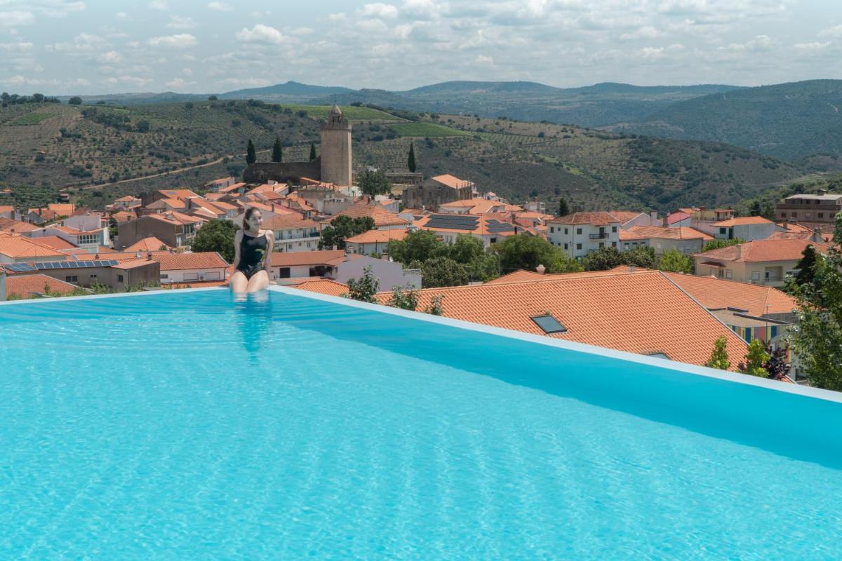 uma mulher parada na beira de uma piscina com vista para uma cidade em Hotel Freixo Douro Superior em Freixo de Espada à Cinta mais 42 fotografias