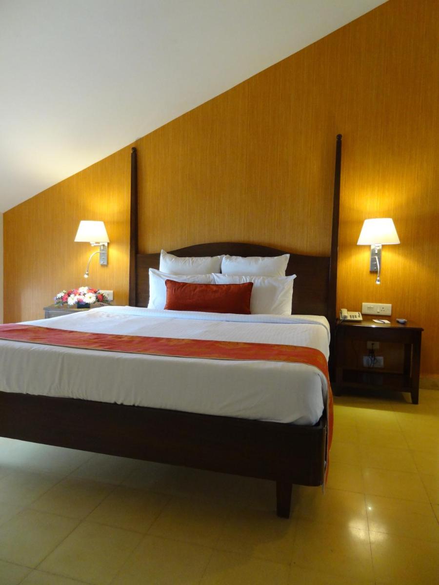 a large bed in a hotel room with two lamps at The Crown Goa in Panaji