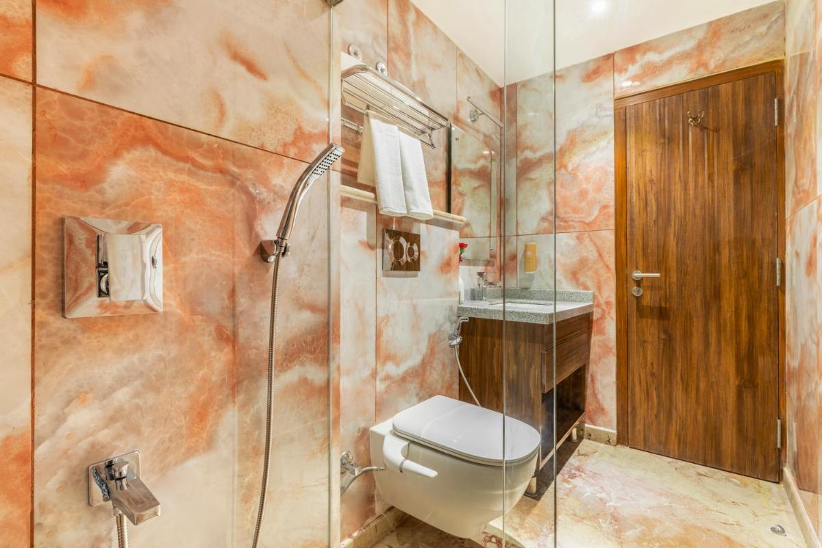 a bathroom with a toilet and a glass shower at The Prominence Mussoorie Road Dehradun in Dehradun
