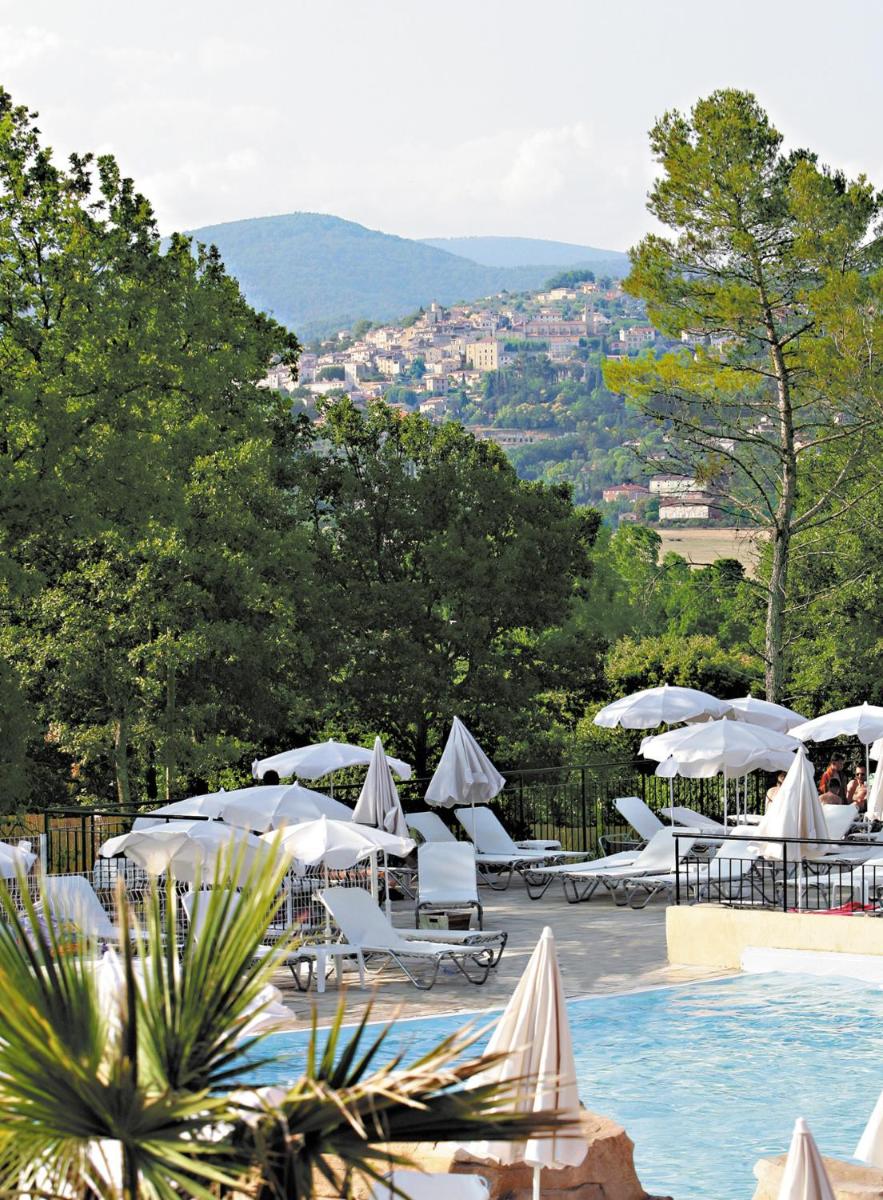 une piscine avec des parasols blancs et une vue sur la ville dans l'établissement Lagrange Vacances Domaine de Fayence, à Fayence