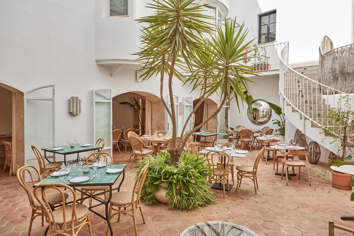 Un restaurante con mesas y sillas y palmeras. en Puro Hotel Oasis Urbano, en Palma de Mallorca