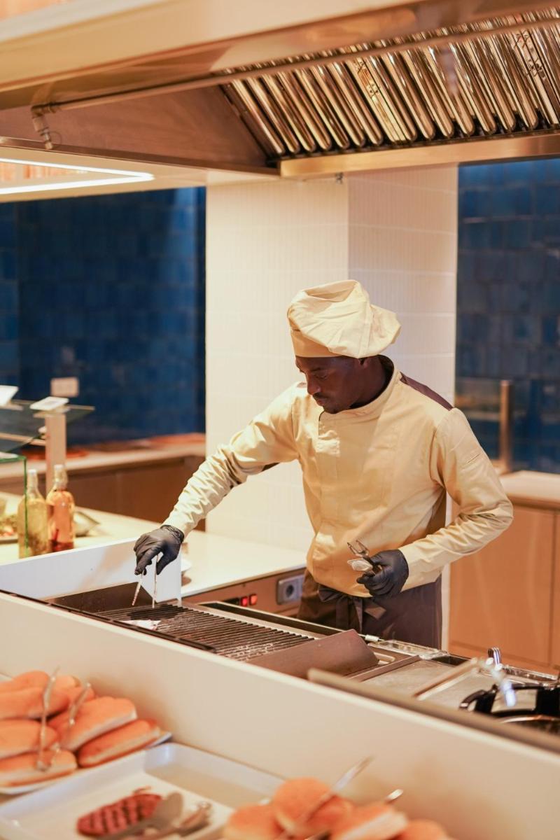 un chef de pie en una cocina preparando comida en Blaumar Hotel, en Salou 109 fotos más