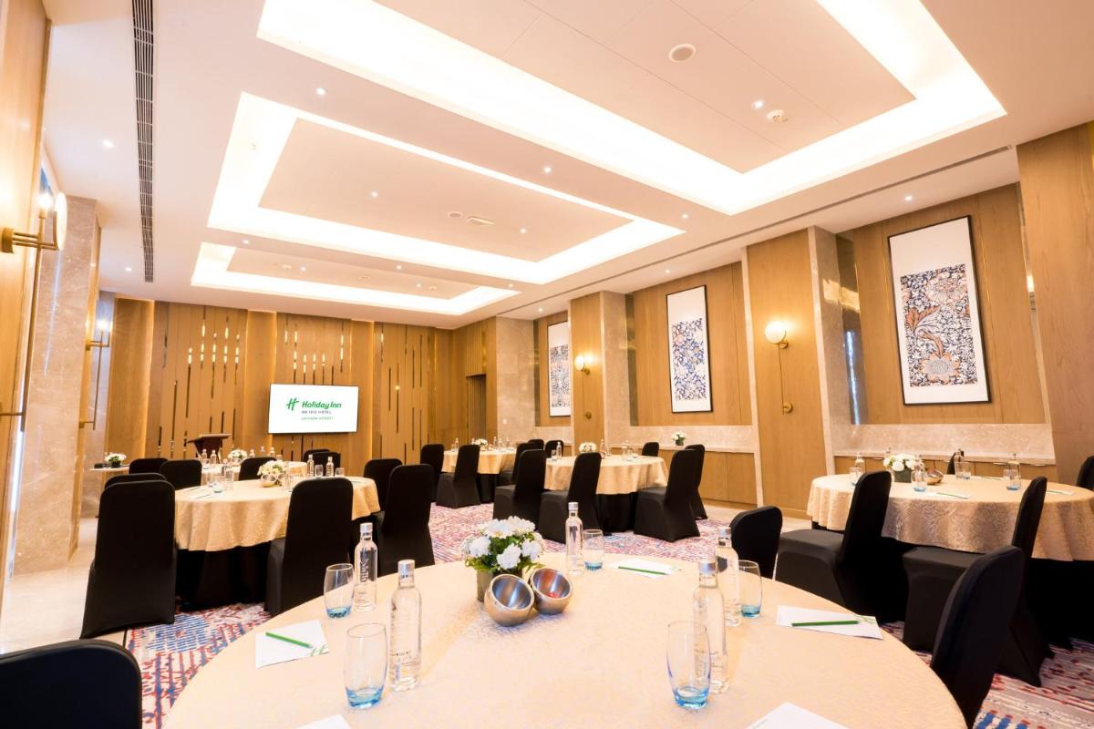 a conference room with tables and chairs and a screen at Holiday Inn Lucknow Airport by IHG in Lucknow