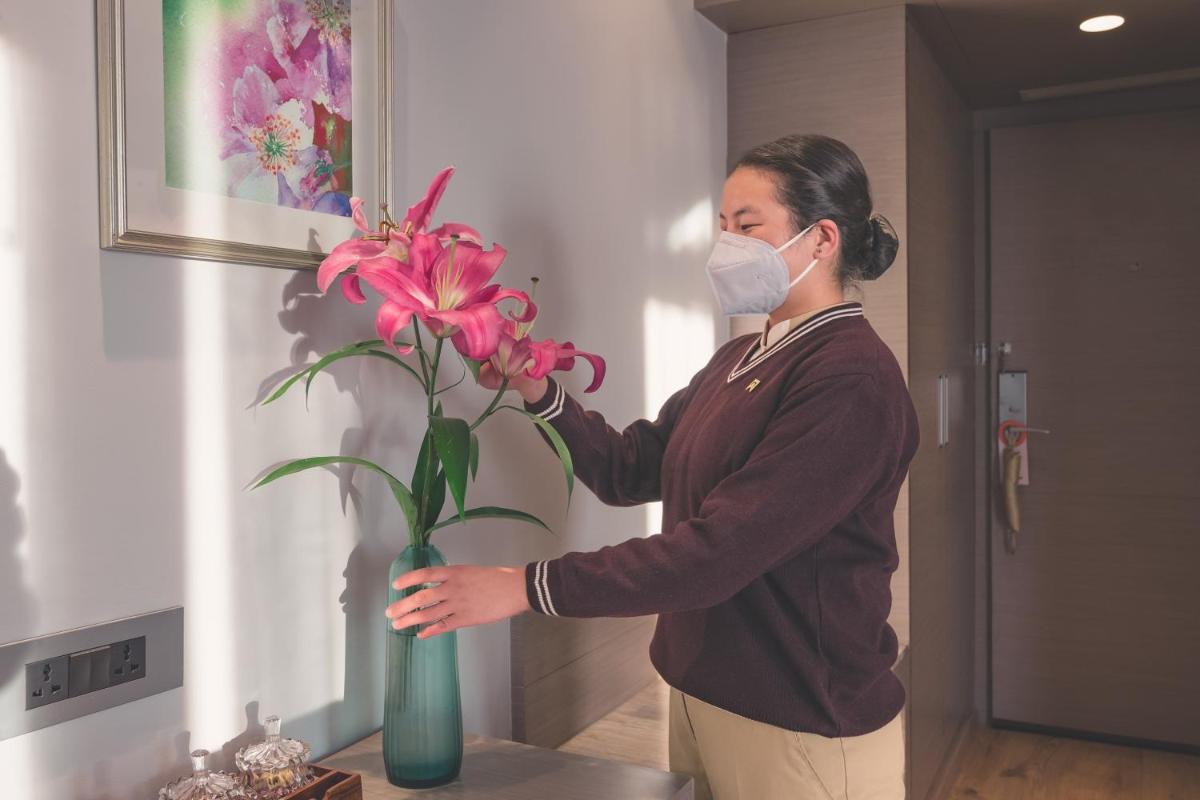 a woman wearing a mask holding a vase with flowers at Welcomhotel by ITC Hotels, Shimla in Shimla