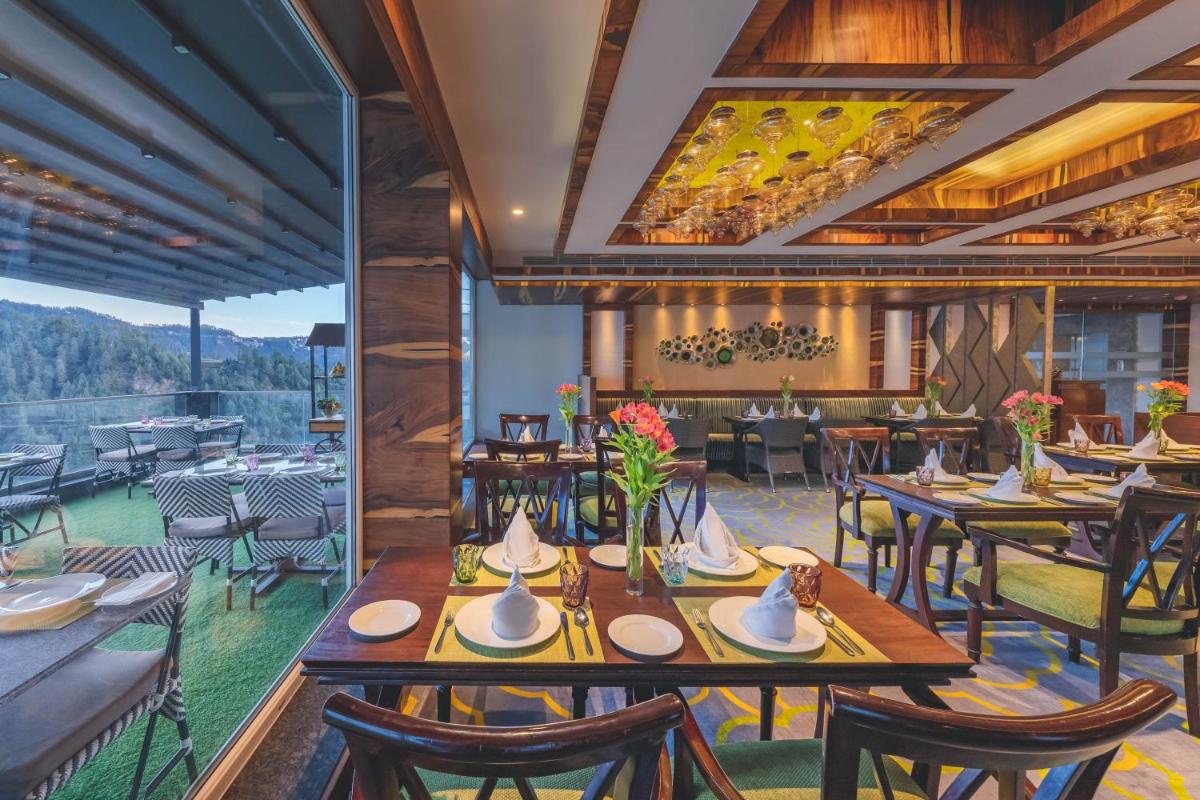 a restaurant with wooden tables and chairs and a large window at Welcomhotel by ITC Hotels, Shimla in Shimla