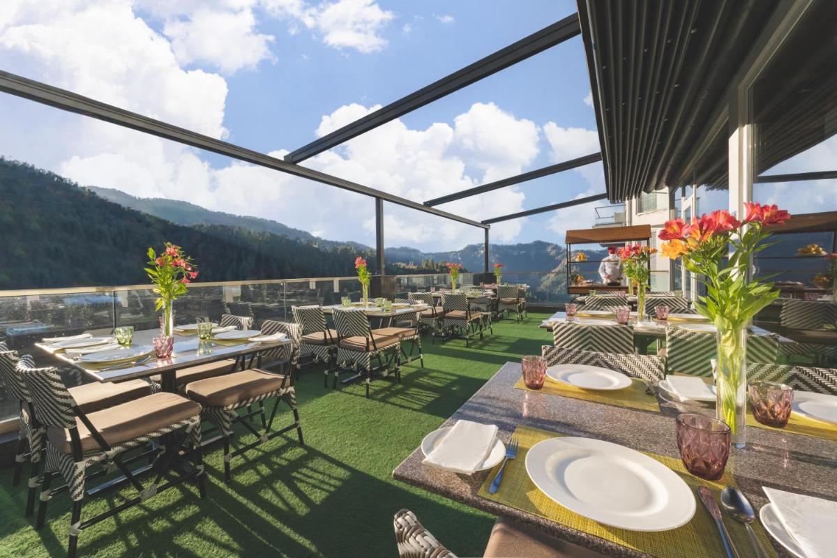 a restaurant with tables and chairs with mountains in the background at Welcomhotel by ITC Hotels, Shimla in Shimla