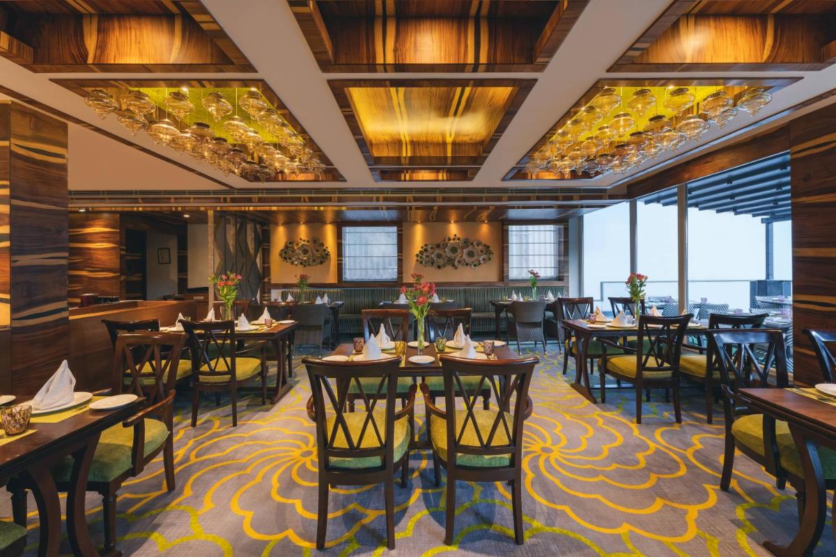 a dining room with tables and chairs and windows at Welcomhotel by ITC Hotels, Shimla in Shimla