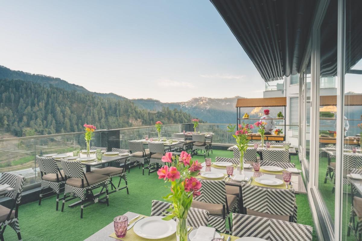 a restaurant with tables and chairs on a balcony at Welcomhotel by ITC Hotels, Shimla in Shimla