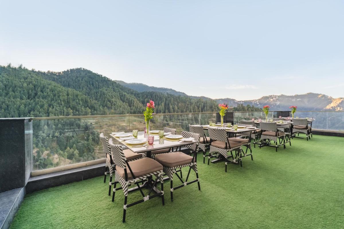 a dining area with tables and chairs on a balcony at Welcomhotel by ITC Hotels, Shimla in Shimla