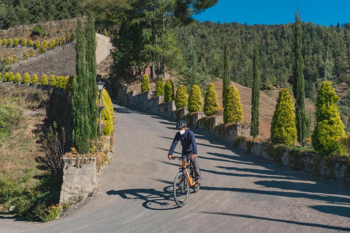 a man riding a bike down a road at Welcomhotel by ITC Hotels, Shimla in Shimla