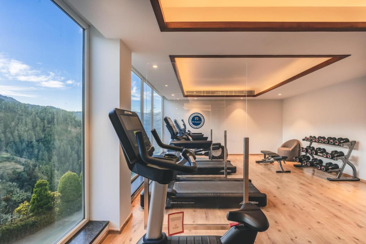 a gym with tread machines and a large window at Welcomhotel by ITC Hotels, Shimla in Shimla