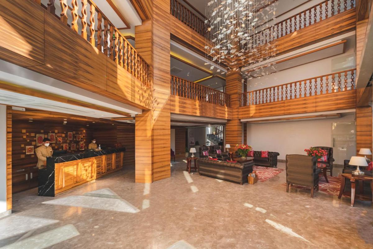 a large lobby with wood paneling and a man standing in a room at Welcomhotel by ITC Hotels, Shimla in Shimla