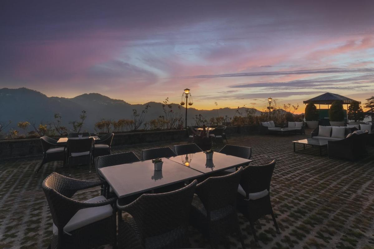 a restaurant with tables and chairs and a sunset at Welcomhotel by ITC Hotels, Shimla in Shimla