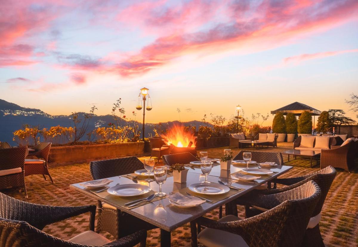 a table set for a meal with a sunset in the background at Welcomhotel by ITC Hotels, Shimla in Shimla