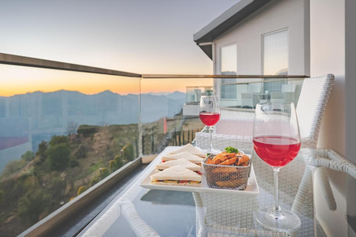 a table with a plate of food and two glasses of wine at Welcomhotel by ITC Hotels, Shimla in Shimla