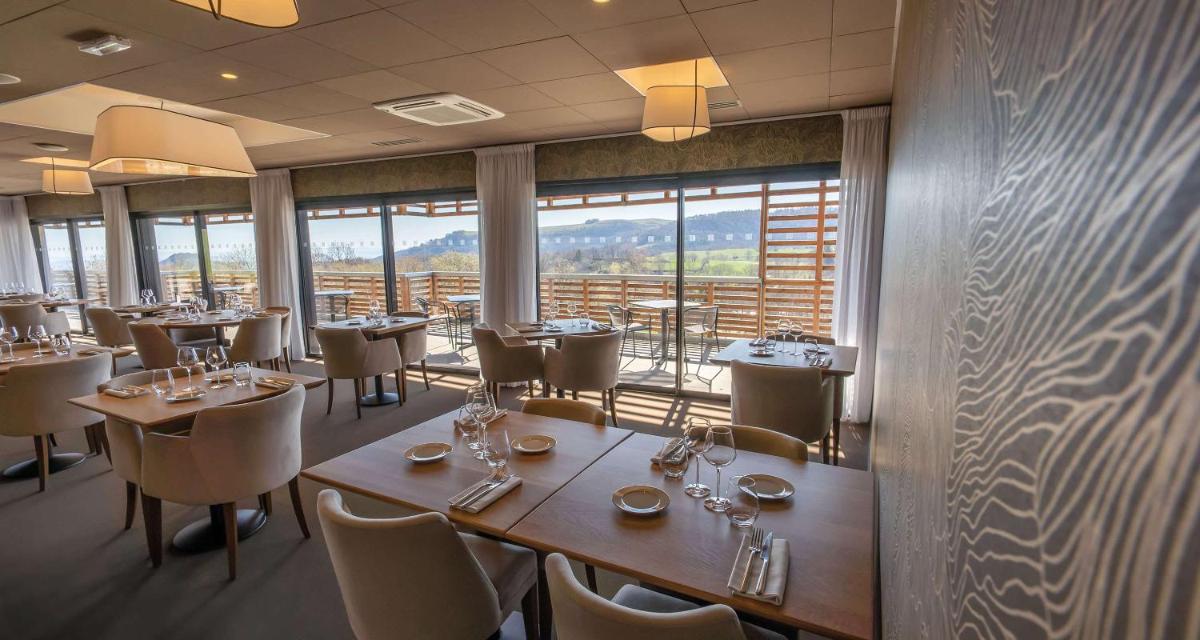 un restaurant avec des tables et des chaises et une grande fenêtre dans l'établissement Mildiss Hotel Spa & Restaurant, BW Signature Collection, à Besse-et-Saint-Anastaise