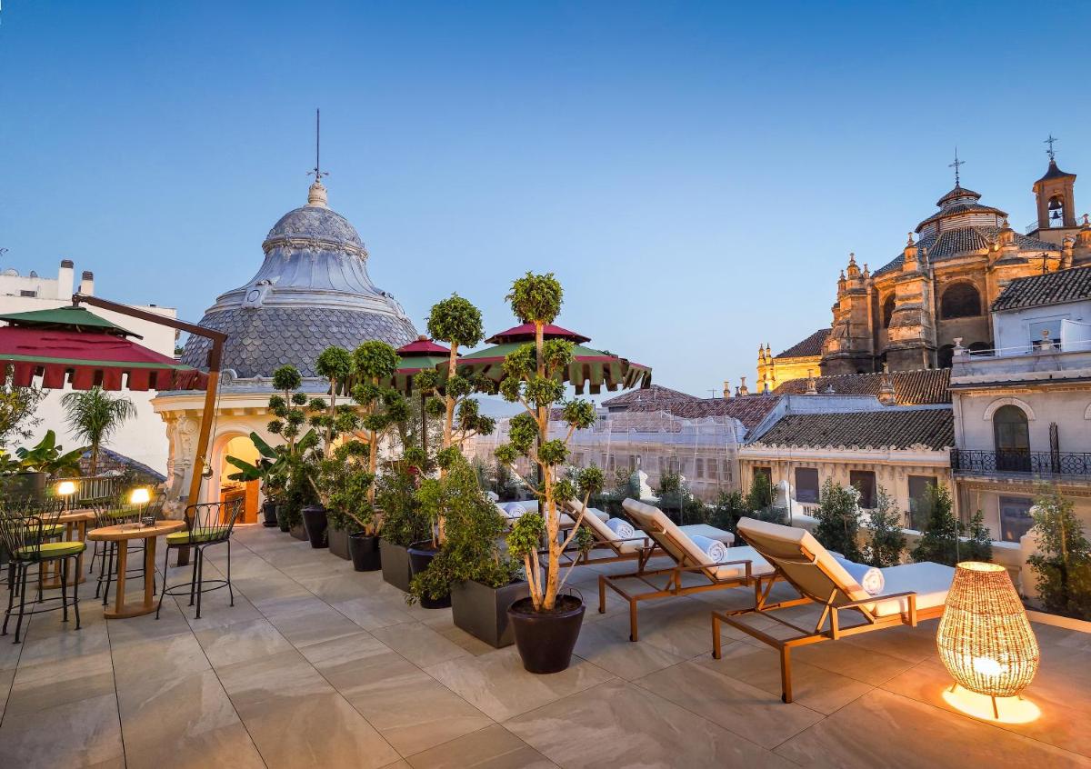 un patio en la azotea con mesas, sillas y edificios en Palacio Gran Vía, a Royal Hideaway Hotel, en Granada