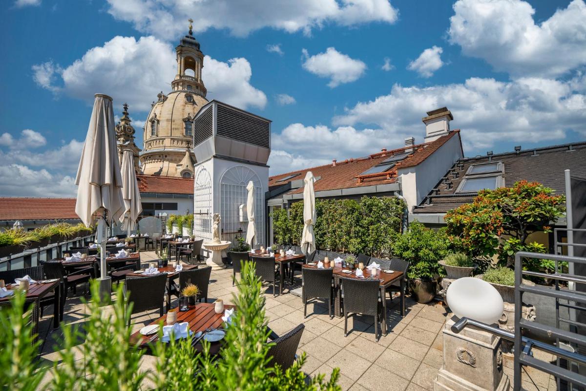 eine Terrasse mit Tischen und Sonnenschirmen vor einem Gebäude in der Unterkunft Hotel Suitess in Dresden eine Terrasse mit Tischen und Sonnenschirmen vor einem Gebäude in der Unterkunft Hotel Suitess in Dresden
