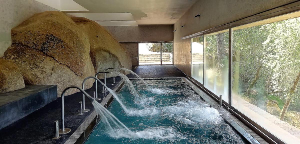 bañera de hidromasaje en una habitación con una roca grande en Hotel Balneario de Retortillo, en Retortillo