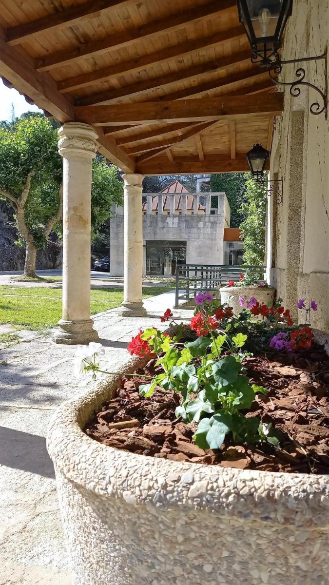 un gran plantador de piedra con flores en un jardín en Hotel Balneario de Retortillo, en Retortillo