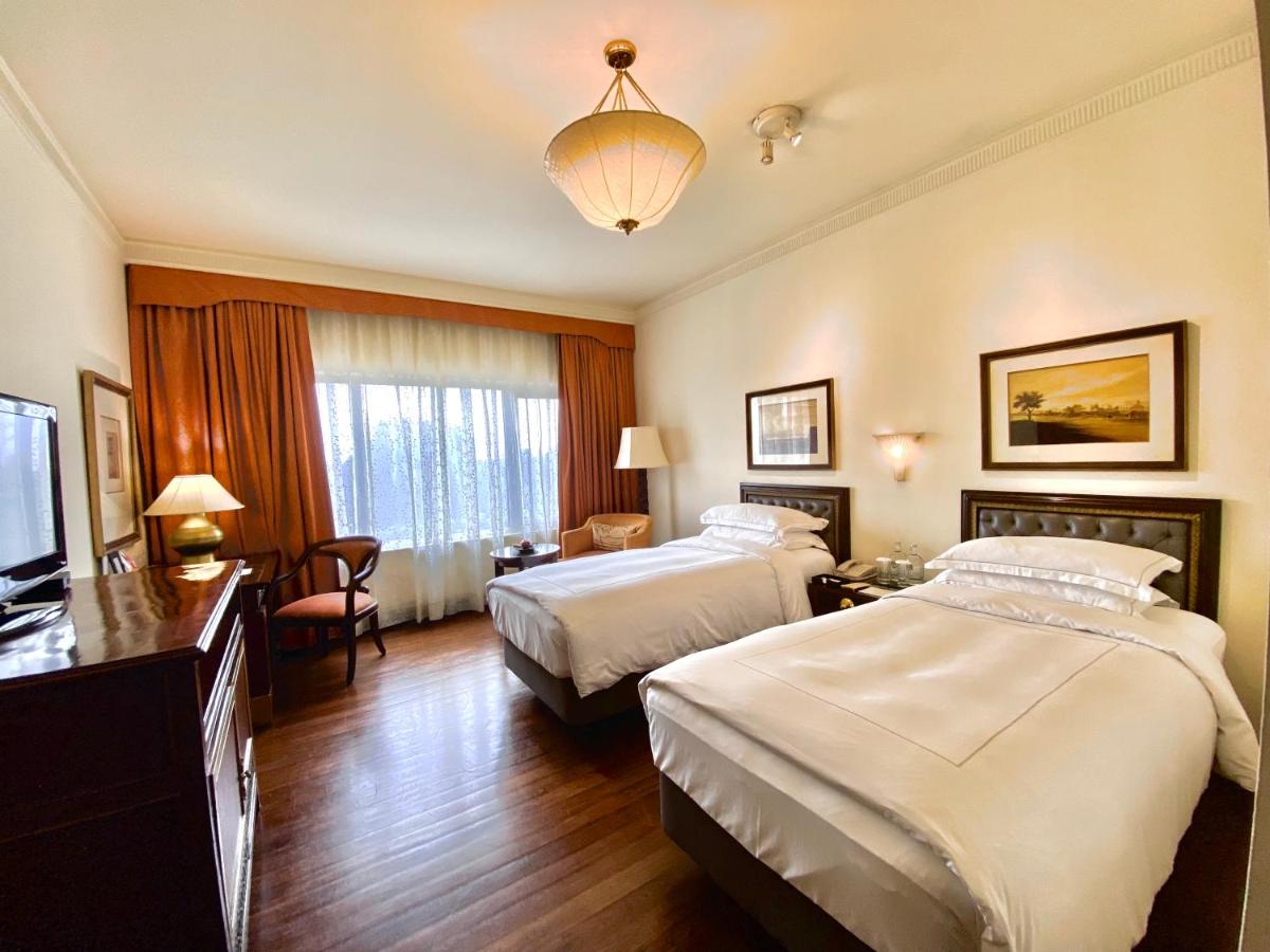 a hotel room with two beds and a television at Taj Bengal in Kolkata