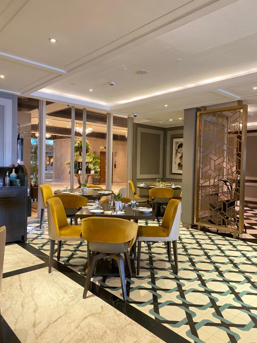 a dining room with tables and yellow chairs at Taj Bengal in Kolkata