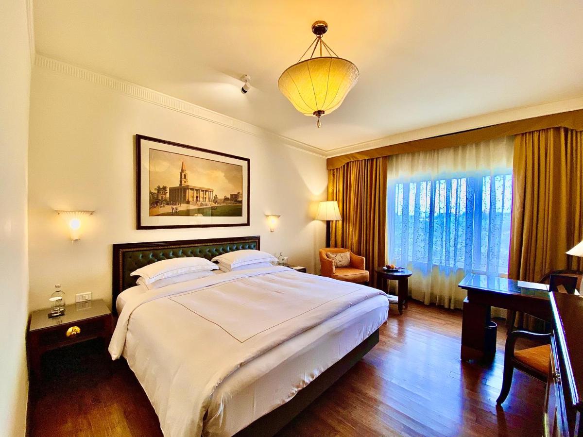 a bedroom with a bed and a desk and a window at Taj Bengal in Kolkata