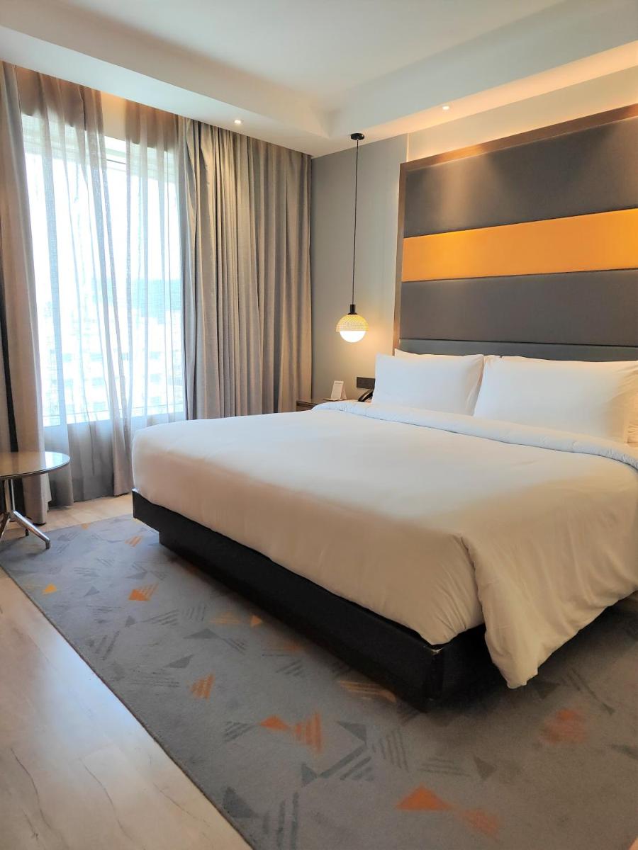 a bedroom with a large bed and a large window at Le Meridien Hyderabad in Hyderabad