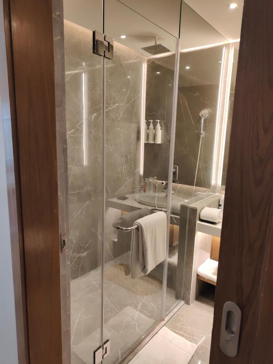 a bathroom with a glass shower with a sink at Le Meridien Hyderabad in Hyderabad