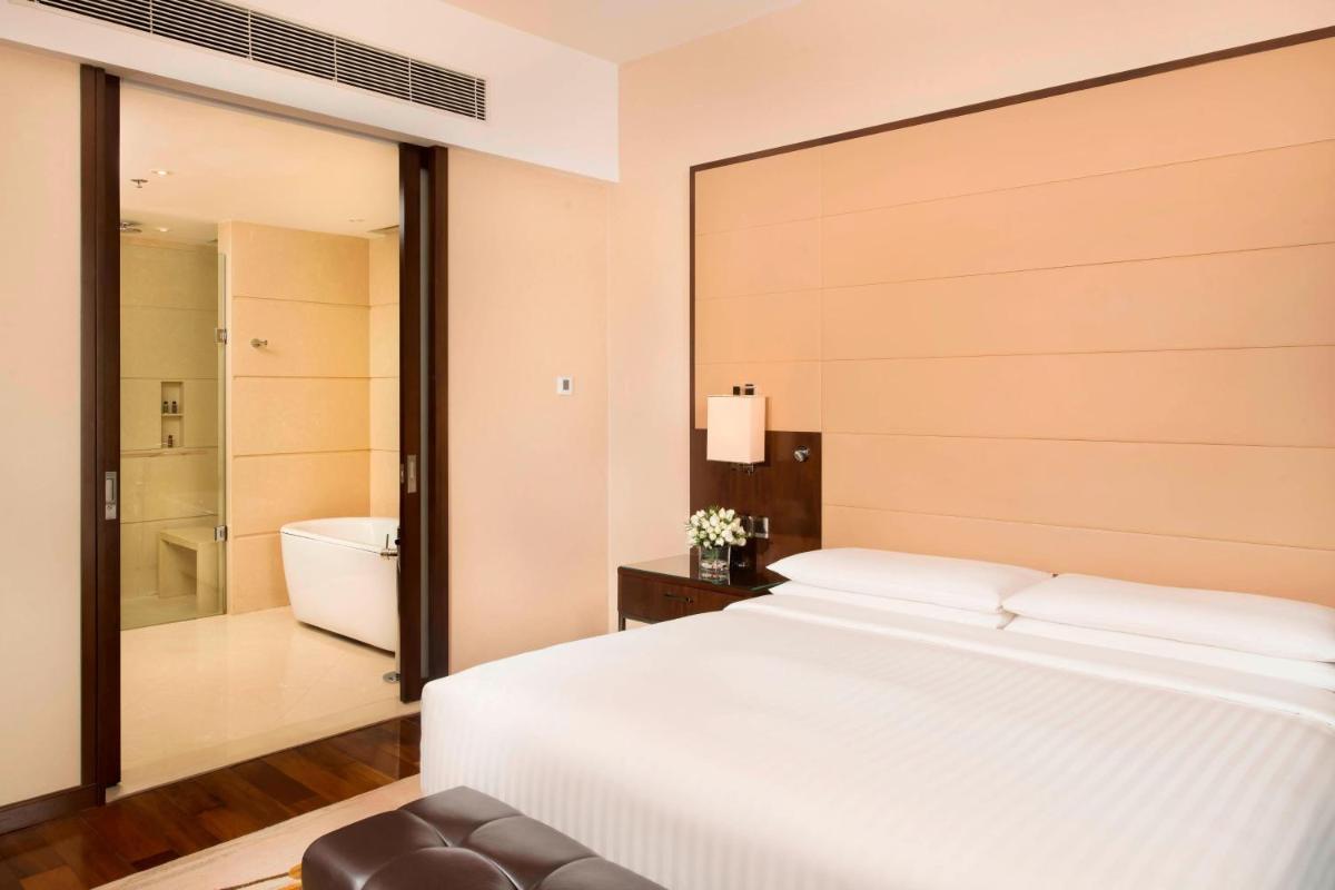 a bedroom with a large white bed and a bathroom at Kochi Marriott Hotel in Cochin